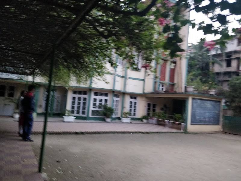Open school courtyard with a vine-covered pergola and the school building at Good Shepherd, Chandmari, Guwahati