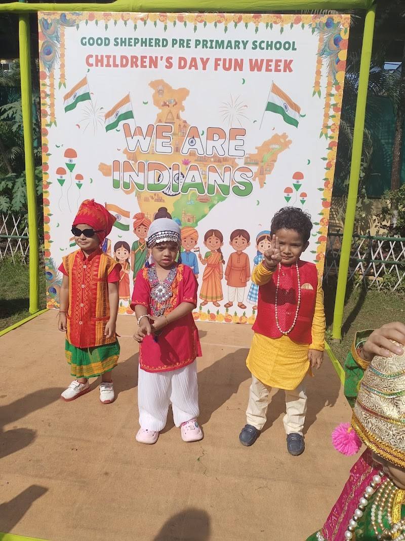 Three young children in colourful costumes stand in front of a Good Shepherd Pre Primary School “Children’s Day Fun Week – We Are Indians” banner in Chandmari, Guwahati