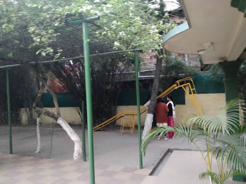 The school playground in Chandmari, Guwahati, with a yellow slide and swings under green trees